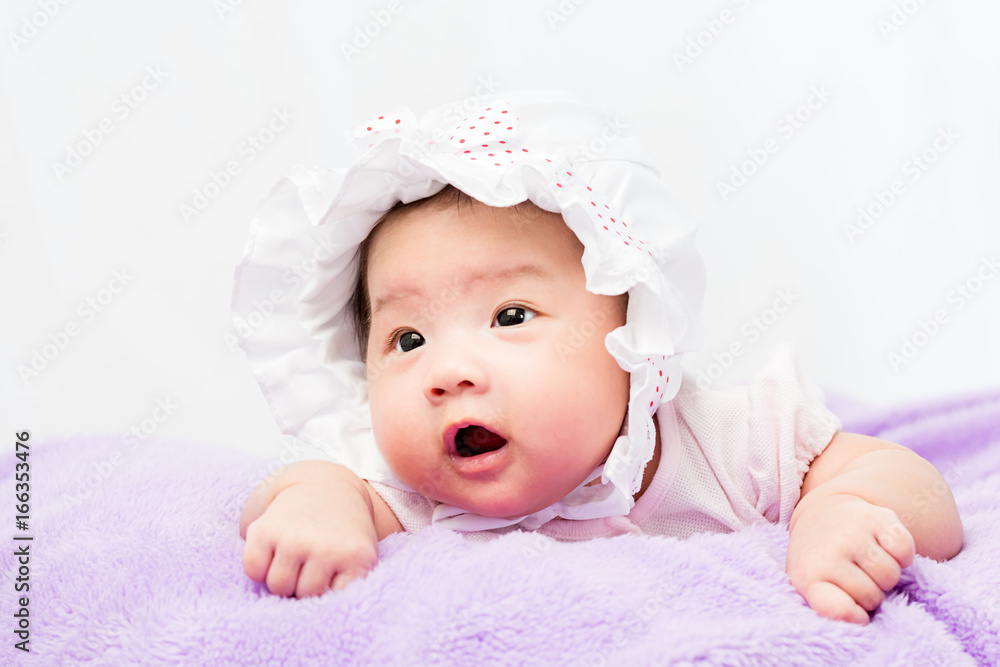 Portrait of a little adorable infant baby girl lying on the tummy on the pillow with head band Portrait of a little adorable infant baby girl lying on the tummy on the pillow with head band