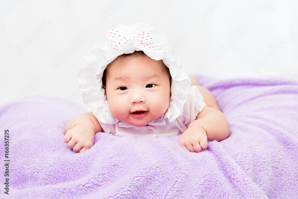 Portrait of a little adorable infant baby girl lying on the tummy on the pillow with head band Portrait of a little adorable infant baby girl lying on the tummy on the pillow with head band