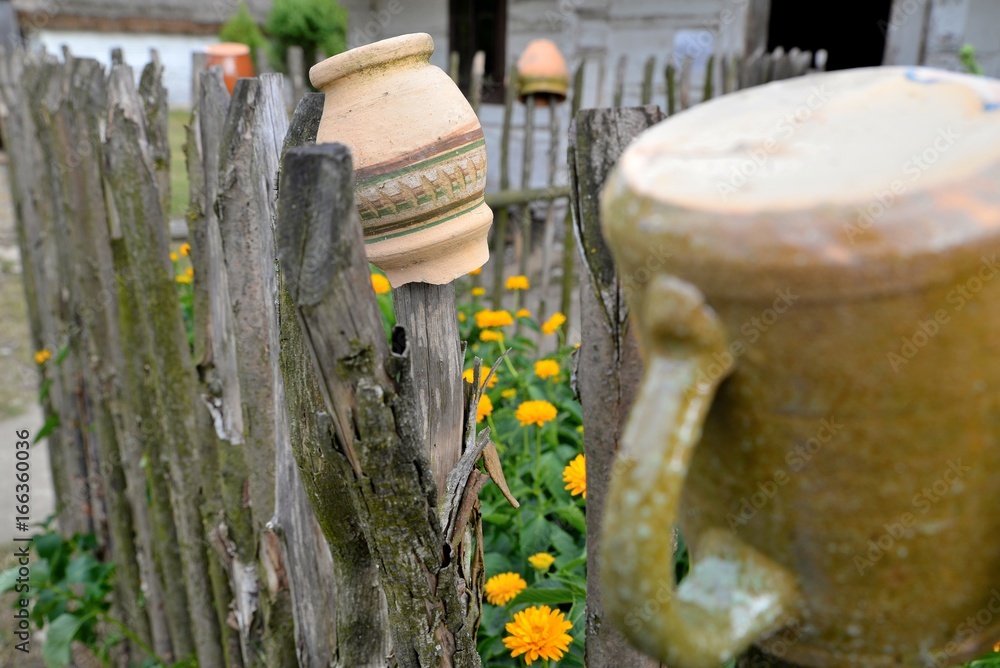 Clay pots drying on a rustic wooden fence