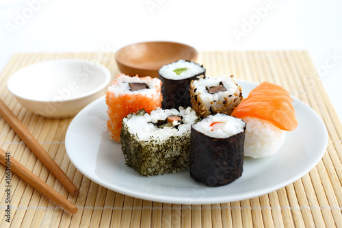 Selection of sushi on bamboo mat with chopsticks.