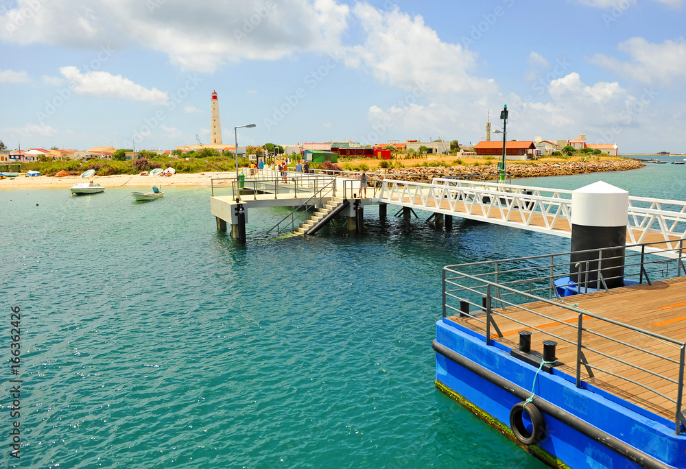 Embarcadero en la Isla de Culatra con el faro de Santa María, playas del Algarve, Portugal