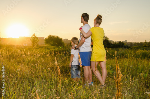 happy family standing outdoors on the field embracing