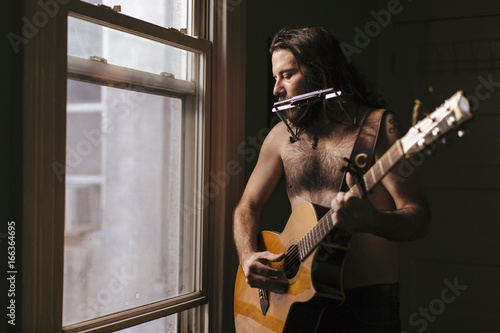 A soulful scruffy musician plays instruments photo