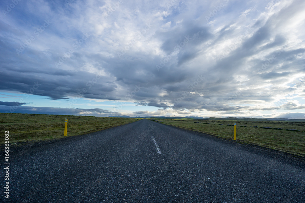 Iceland - Bolt upright street between wide green land and mountains Iceland - Bolt upright street between wide green land and mountains