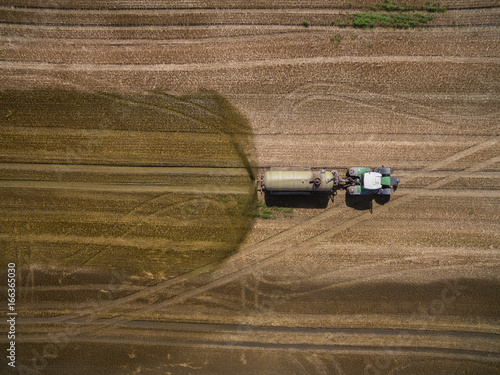 
aerial view of a tractor with a trailer fertilizes a freshly plowed agriculural field with manure in germany photo