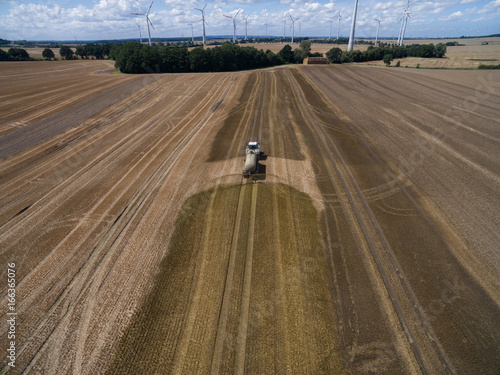  aerial view of a tractor with a trailer fertilizes a freshly plowed agriculural field with manure in germany