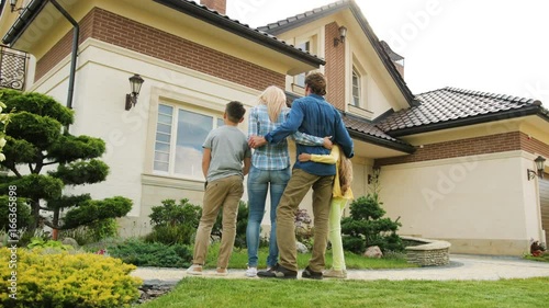 Caucasian family standing faces to the new home and hugging. View from the bottom. photo