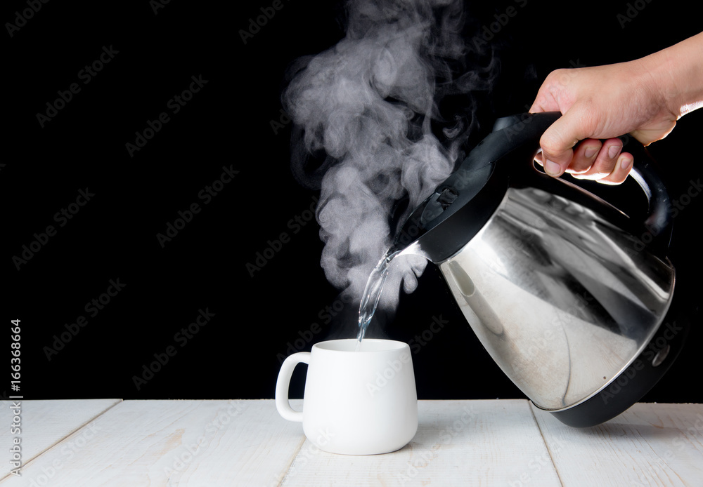 kettle pouring boiling water into a cup with smoke on wood table Stock  Photo