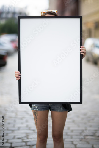 poster mockup - girl holds a frame with a blank white copy space
