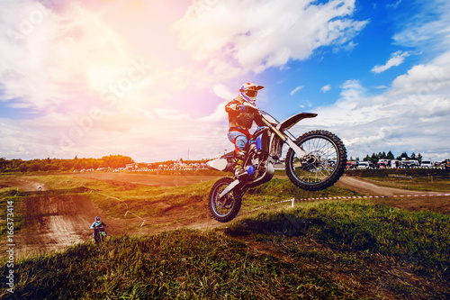 racer on mountain bike participates in motocross race, takes off and jumps on springboard, against the background of the participants. Close-up. concept of extreme rest, sports racing. ray of light