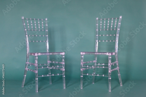 Transparent plastic chairs on a green background in a photo studio