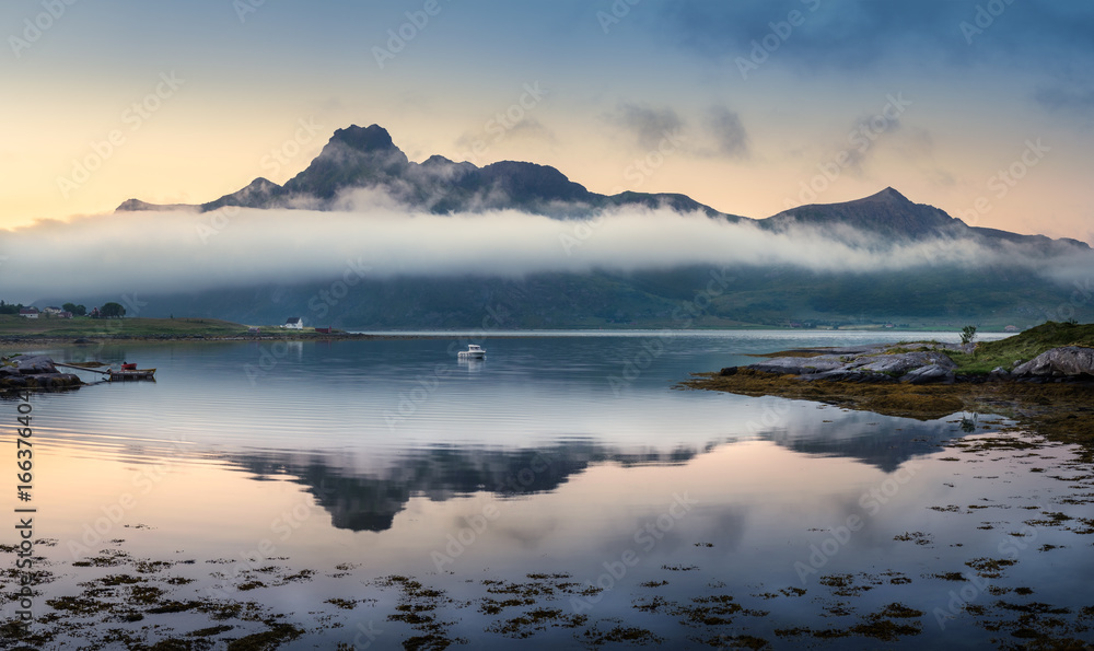 Scenic landscape with mountain reflection and low clouds at summer night in Lofoten, Norway Scenic landscape with mountain reflection and low clouds at summer night in Lofoten, Norway