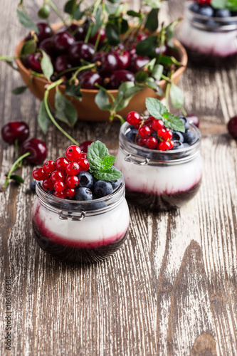 Summer yogurt dessert with sour cherry, red currant and blueberry sweet sauce