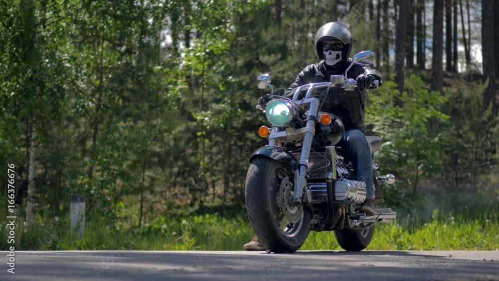 A motorcyclists starts up his motorcycle and drives away.