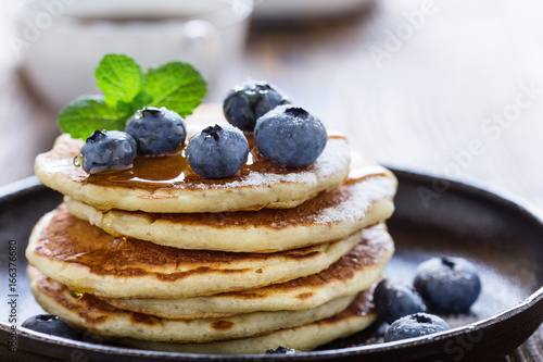 Blueberry buttermilk pancakes with maple syrup on rustic table