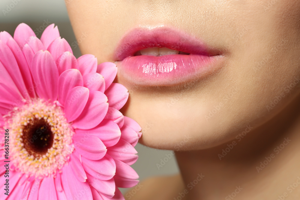 Young woman with beautiful lips and gerbera flower near face, closeup