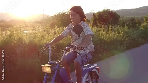 Boy ride moped at sunset photo