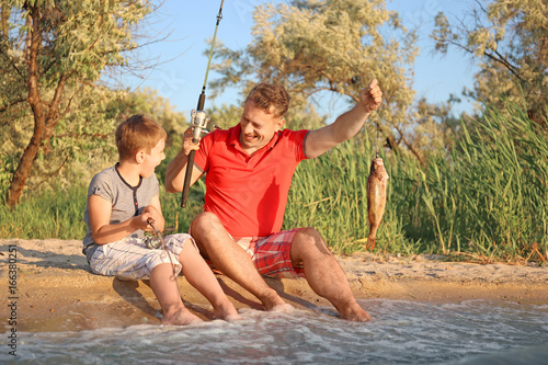 Dad and son fishing from sh...