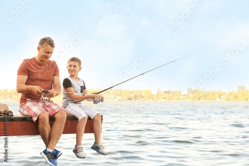 Dad and son fishing from pi...