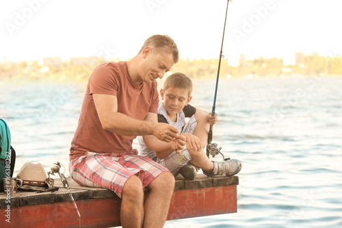 Dad and son fishing from pi...