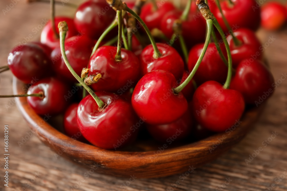 Wooden plate with fresh ripe cherries on table Wooden plate with fresh ripe cherries on table