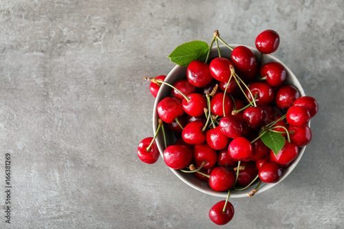 Fotografia Bowl with fresh ripe cherries on grey background