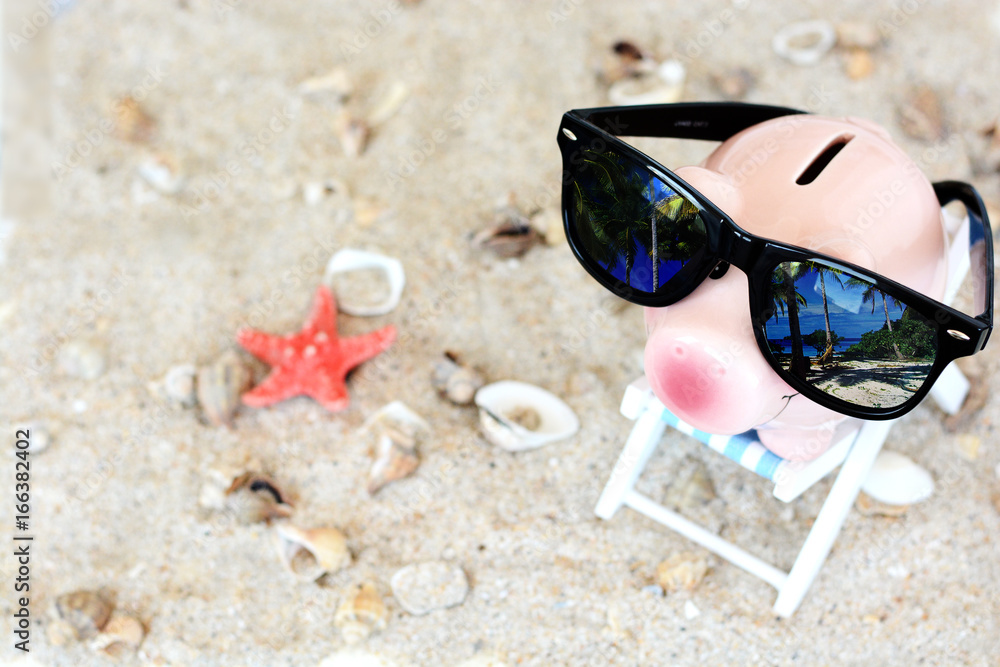Savings for a holiday concept with piggy bank with sunglasses in a beach chair