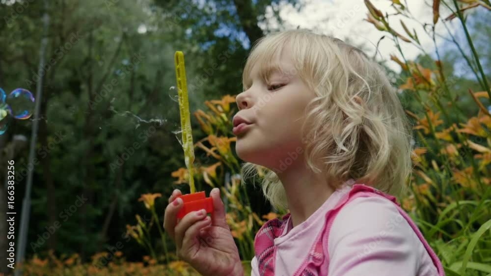 The pretty child amusing herself by blowing bubbles with the soap solution. Slow motion. HD The pretty child amusing herself by blowing bubbles with the soap solution. Slow motion. HD