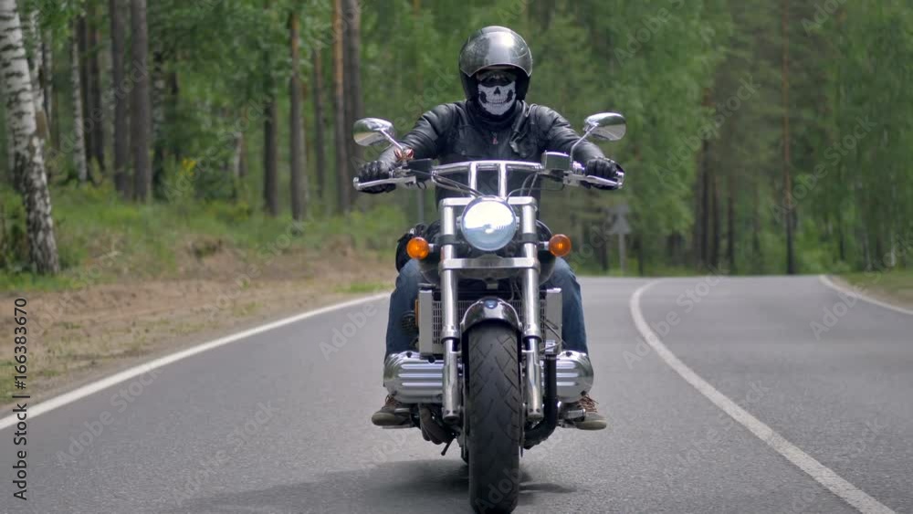 A motorcyclist rides a country road and grips both handlebars. A motorcyclist rides a country road and grips both handlebars.