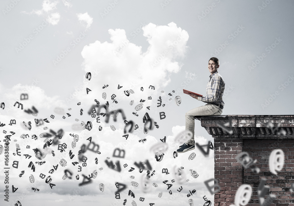 Man on roof edge reading book and symbols flying around Man on roof edge reading book and symbols flying around