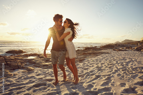 Romantic young couple on beach during sunset photo