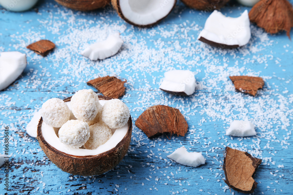 Coconuts with candies on blue wooden table Coconuts with candies on blue wooden table
