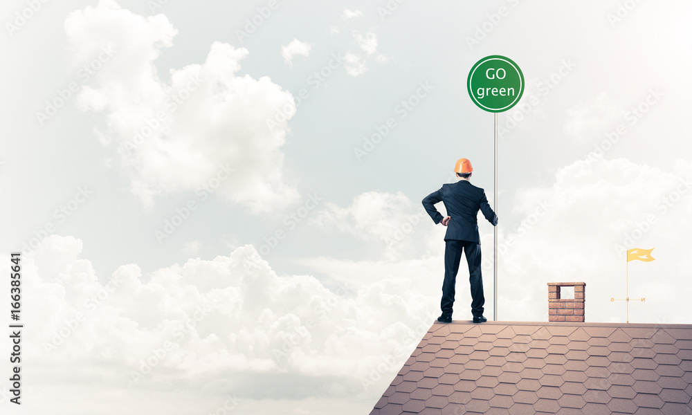 Obraz premium Businessman in suit on house top with ecology concept signboard.