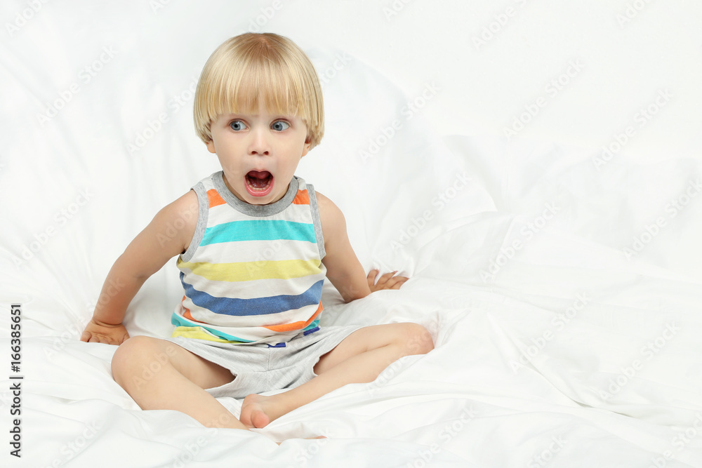 Little boy with open mouth sitting in white bed Little boy with open mouth sitting in white bed