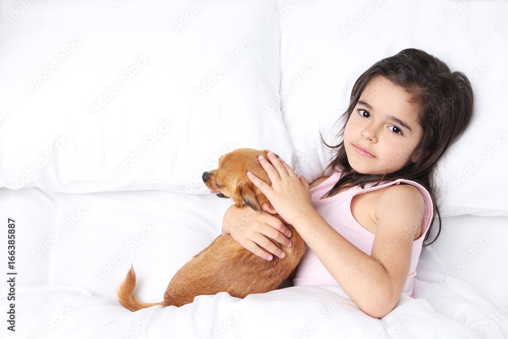 Beautiful little girl with dog sleeping in white bed