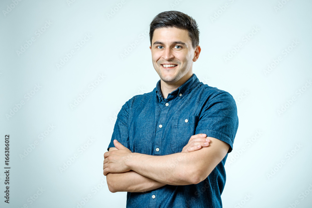 Studio shot of young man with crossed hands looking at the camera Studio shot of young man with crossed hands looking at the camera