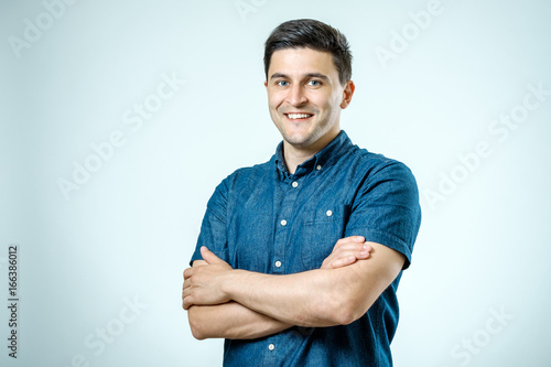 Studio shot of young man with crossed hands looking at the camera