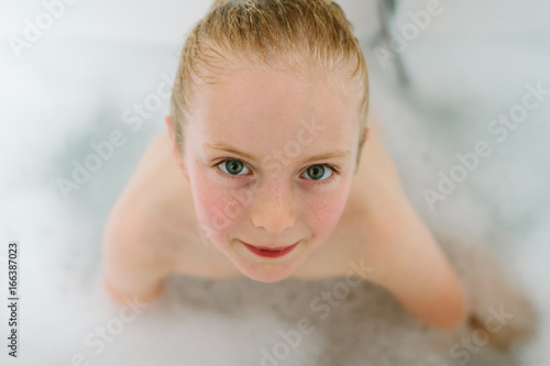 A little girl with wet hair in a bubble bath photo