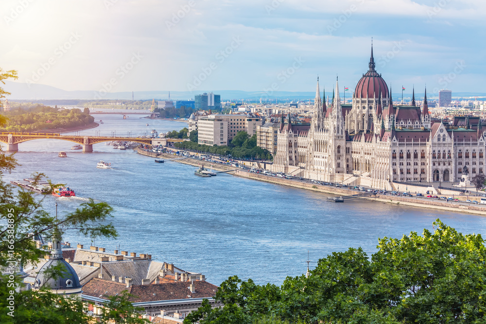 Obraz premium Koncepcja podróży i turystyki europejskiej. Parlament i brzeg rzeki w Budapeszcie na Węgrzech ze statkami wycieczkowymi w letni dzień z błękitnym niebem i chmurami