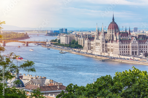 Travel and european tourism concept. Parliament and riverside in Budapest Hungary with sightseeing ships during summer day with blue sky and clouds
