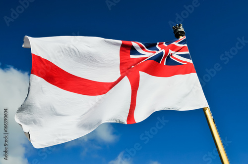 Royal Navy white ensign flying from a warship while docked.