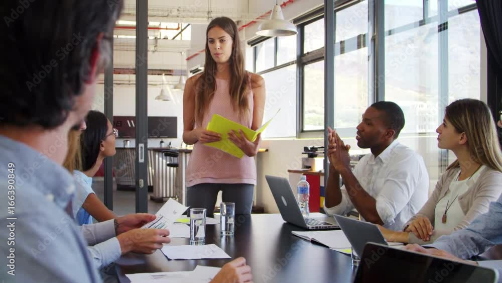 Female manager addresses meeting and hands out documents Female manager addresses meeting and hands out documents