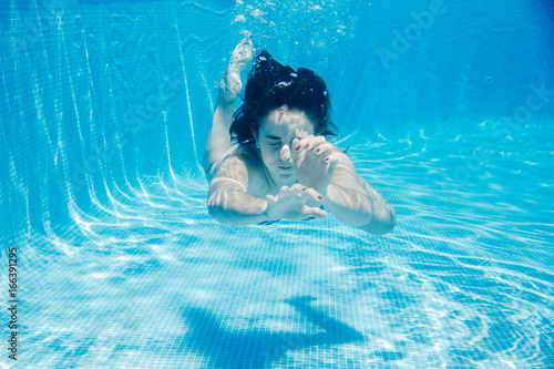 .Young woman enjoying the pool on a sunny summer day. Taking photos under water playful. Lifestyle portrait.