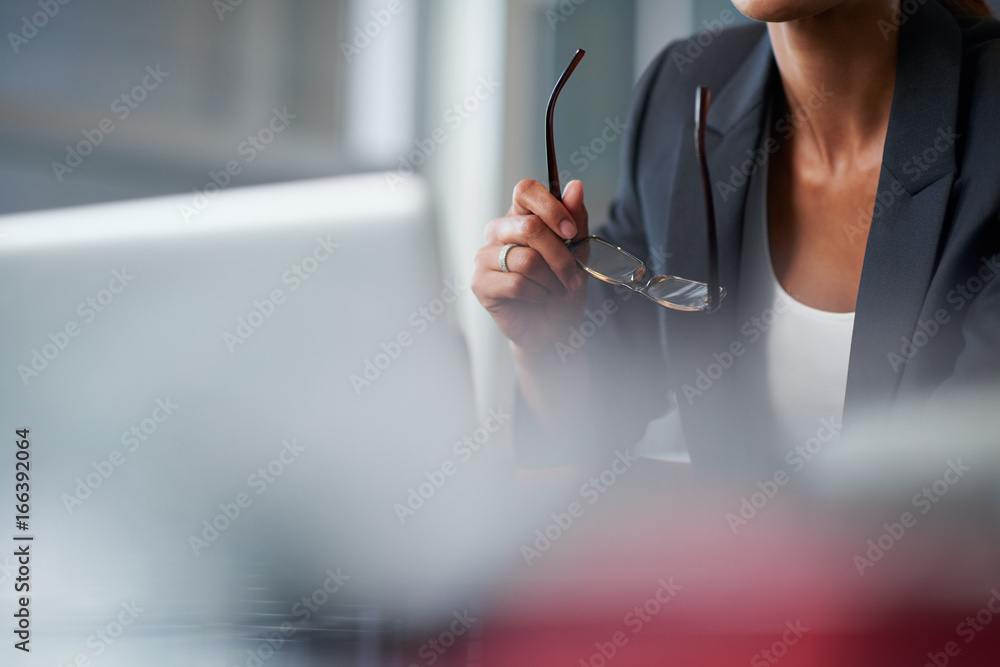 business woman thinking while holding spectacles