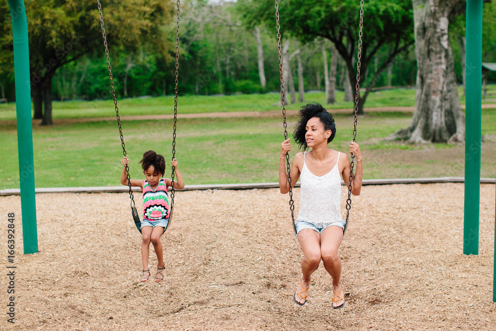 Mother and daughter having fun on playground swing Mother and daughter having fun on playground swing