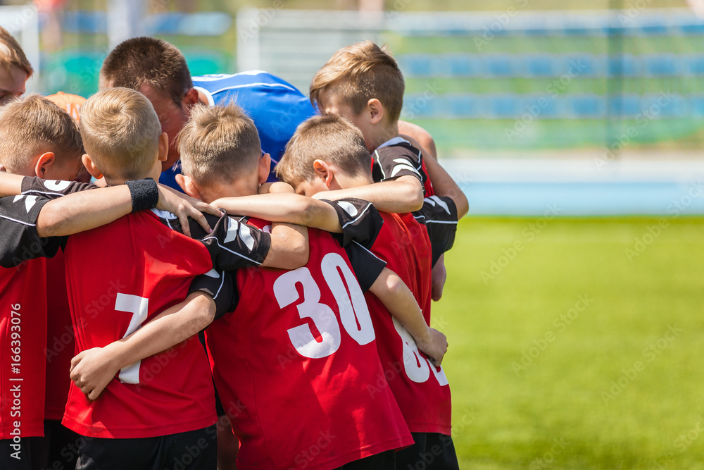Children sports soccer team. Kids standing together on the football pitch. Soccer coach motivational team talk. Youth football soccer coach motivating players before match.