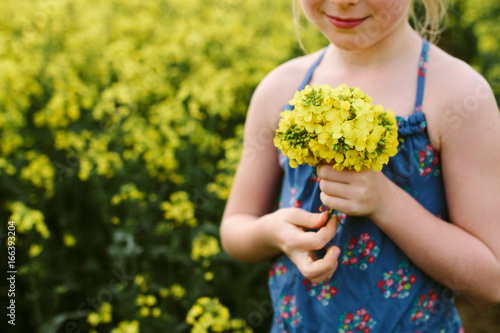 A little girl holding a posy of yellow rape flowers