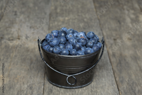 Small bucket of blueberries sitting on a rustic wood background. photo