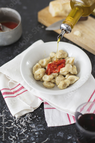Pourng olive oil on homemade gnocchi dish and tomato sauce photo