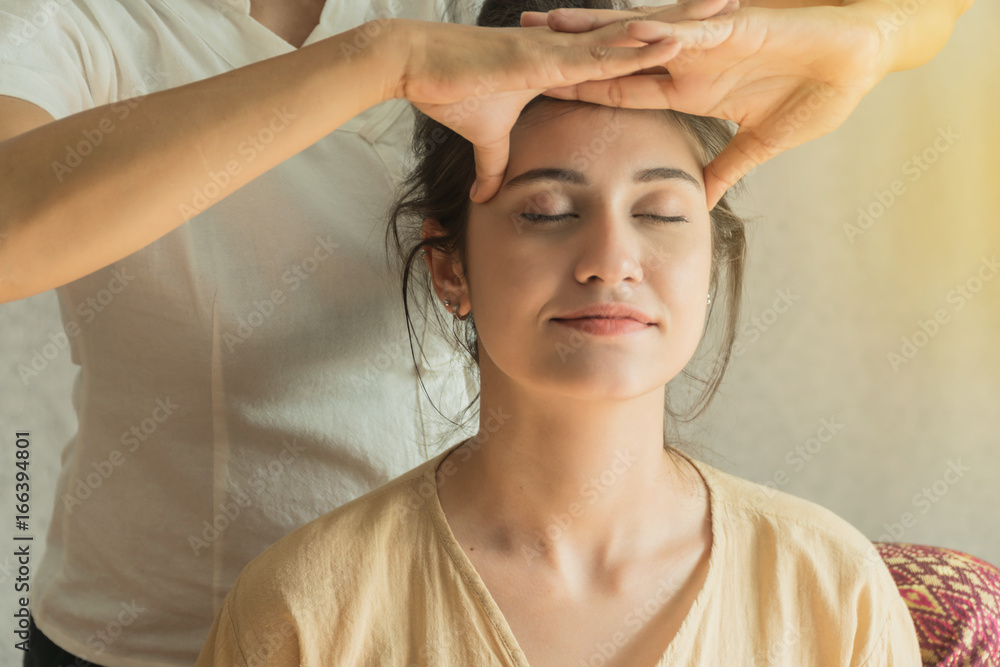 Naklejka premium Beautiful Asian young woman getting head thai massage in spa.She is very relaxed. concept relaxation and health spa.